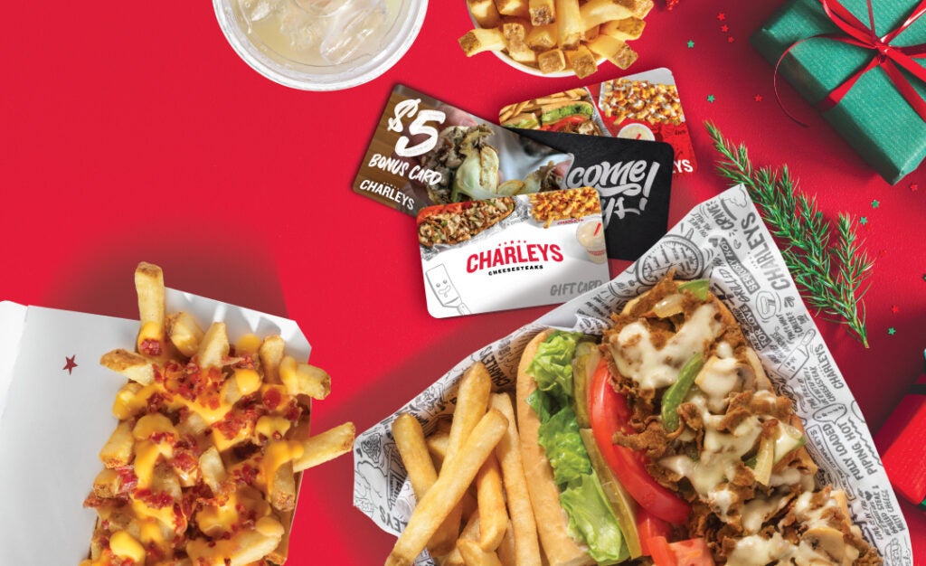 Charleys Cheesesteaks gift cards and bonus cards on a table with holiday decorations. Charleys gift card