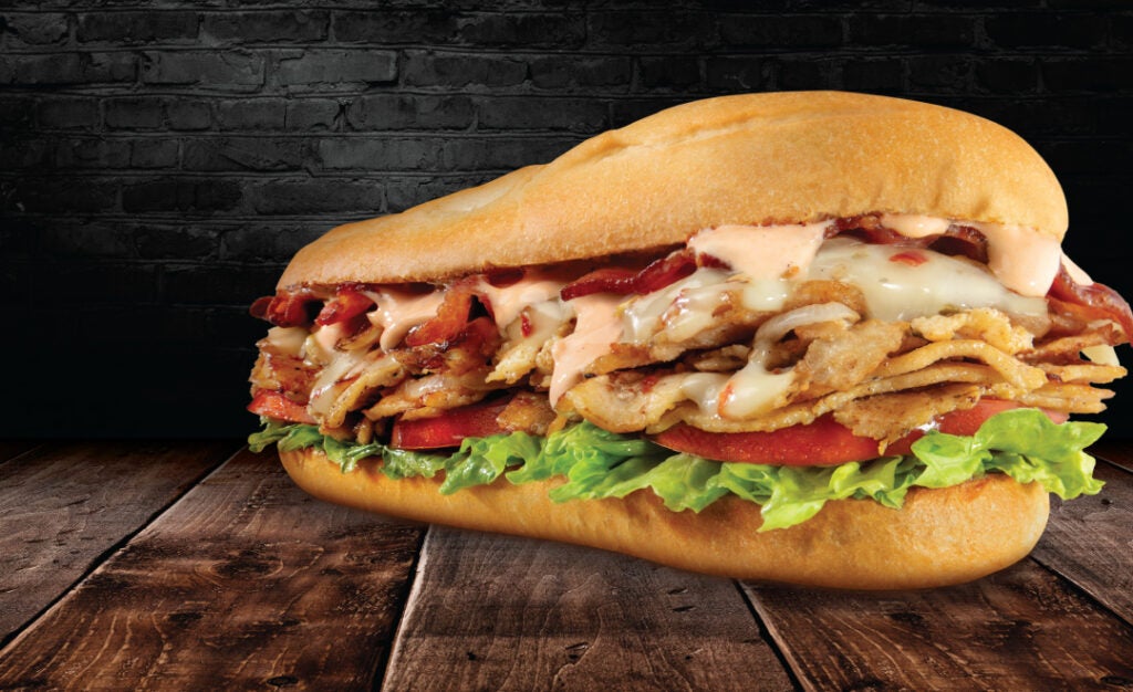 The Bacon Chipotle Cheesesteak from Charleys on a wooden table. Charleys Cheesesteaks.